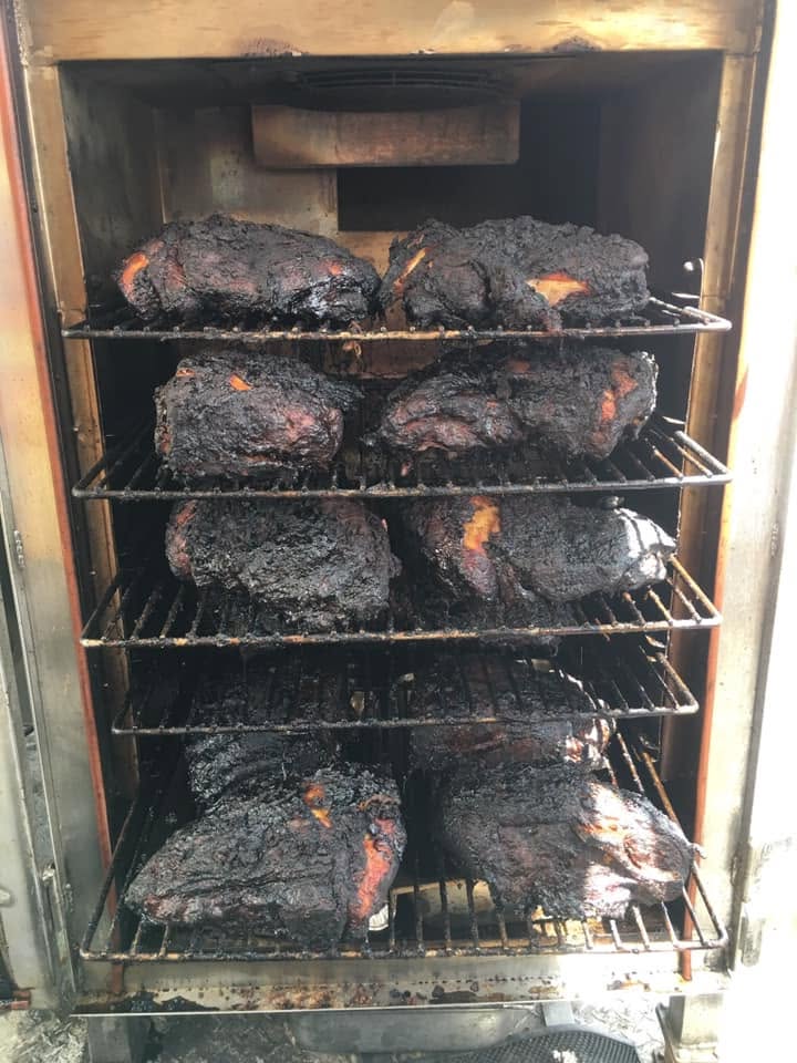 Beef brisket with a deep smoke bark resting in the pit