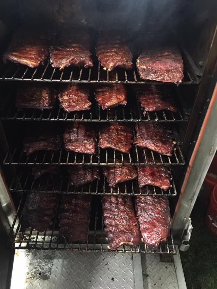 Racks of ribs slow-smoking on the racks inside the pit